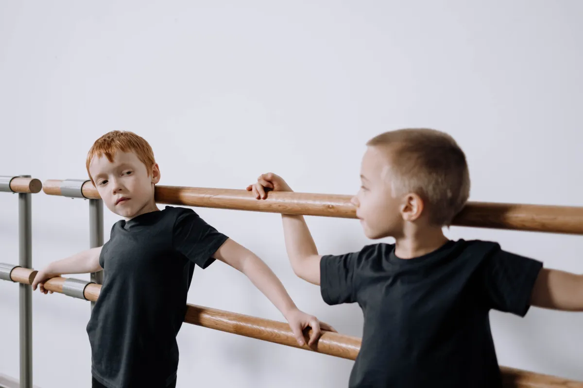 Two young boys holding the barre during a ballet class
